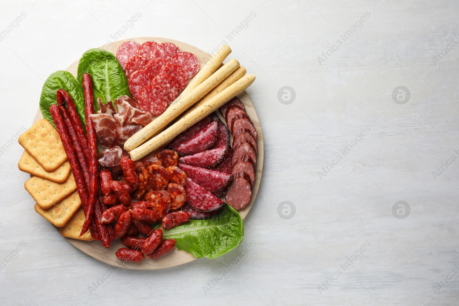 Photo of Different smoked sausages and other snacks on white table, top view. Space for text