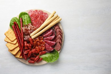 Photo of Different smoked sausages and other snacks on white table, top view. Space for text