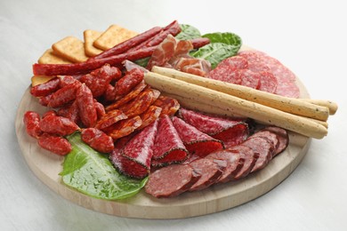 Photo of Different smoked sausages and other snacks on white table, closeup