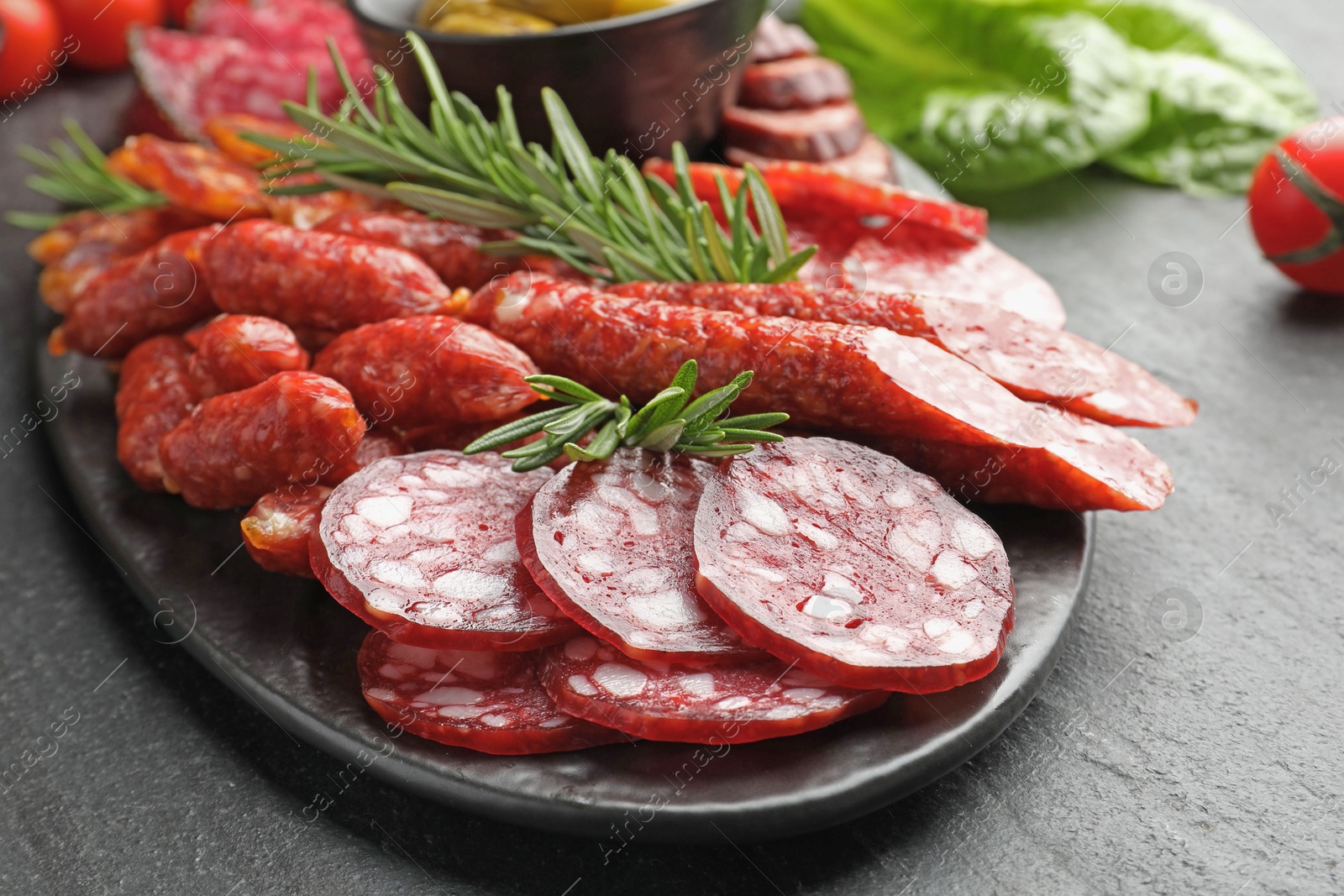 Photo of Different smoked sausages and rosemary on black table, closeup