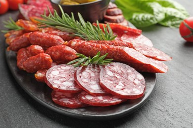 Photo of Different smoked sausages and rosemary on black table, closeup