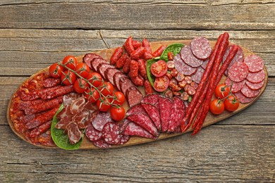 Photo of Different smoked sausages, ham and tomatoes on wooden table, top view