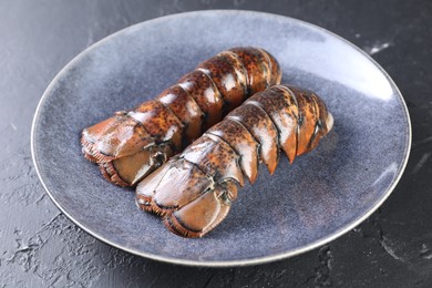 Photo of Raw lobster tails on black table, closeup