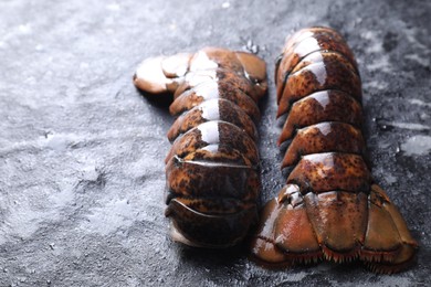 Photo of Raw lobster tails on dark table, closeup. Space for text