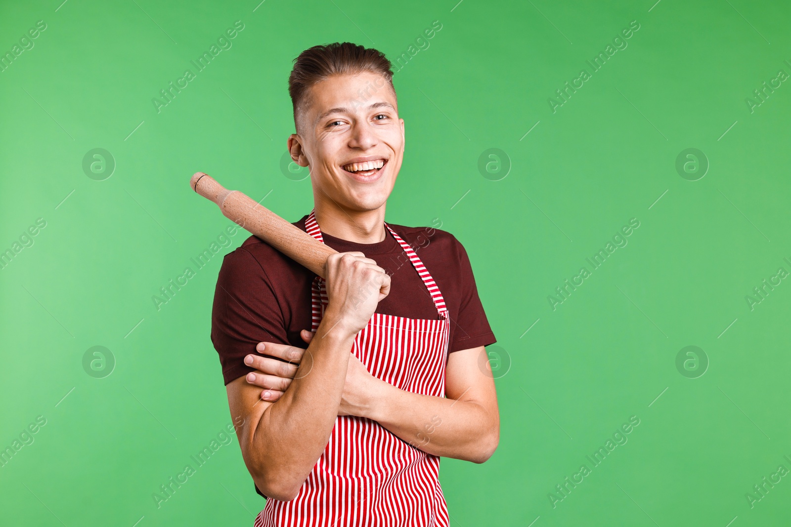 Photo of Happy man with rolling pin on green background