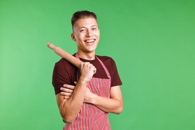 Happy man with rolling pin on green background