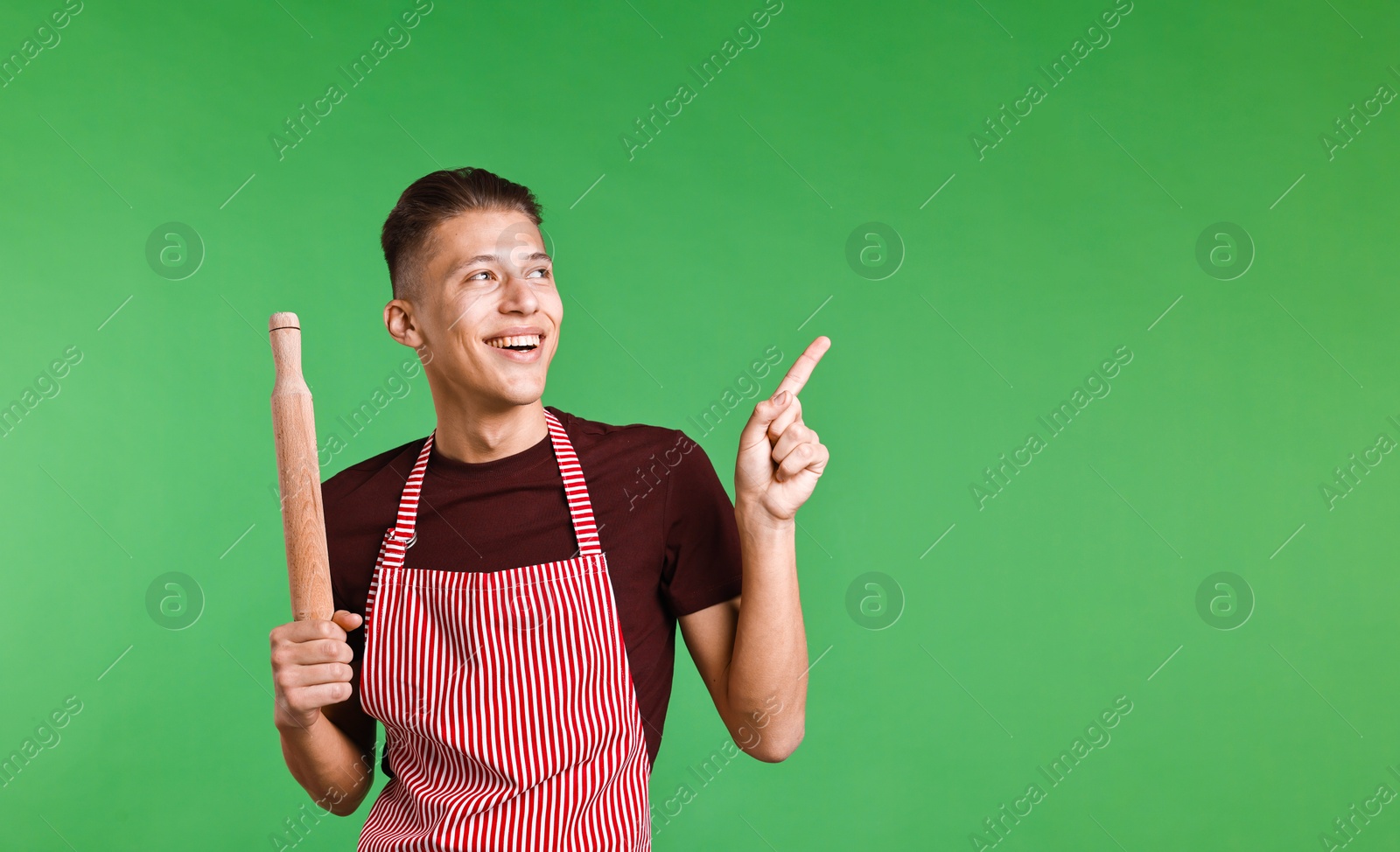 Photo of Happy man with rolling pin pointing at something on green background