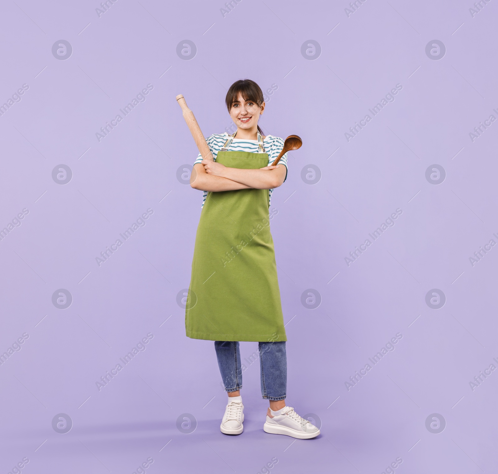 Photo of Woman with rolling pin and ladle on violet background