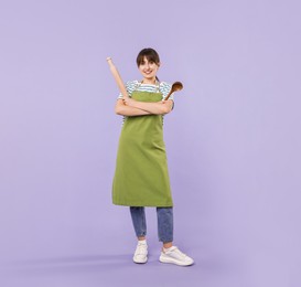 Woman with rolling pin and ladle on violet background