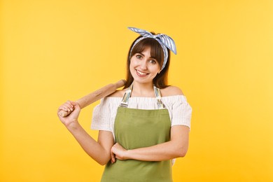 Photo of Happy woman with rolling pin on yellow background