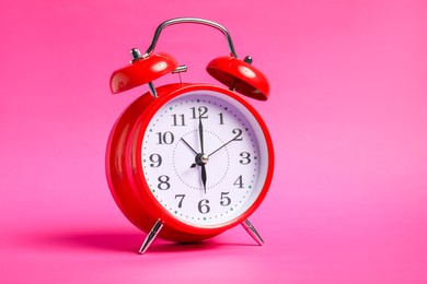 Photo of One red alarm clock on bright pink background