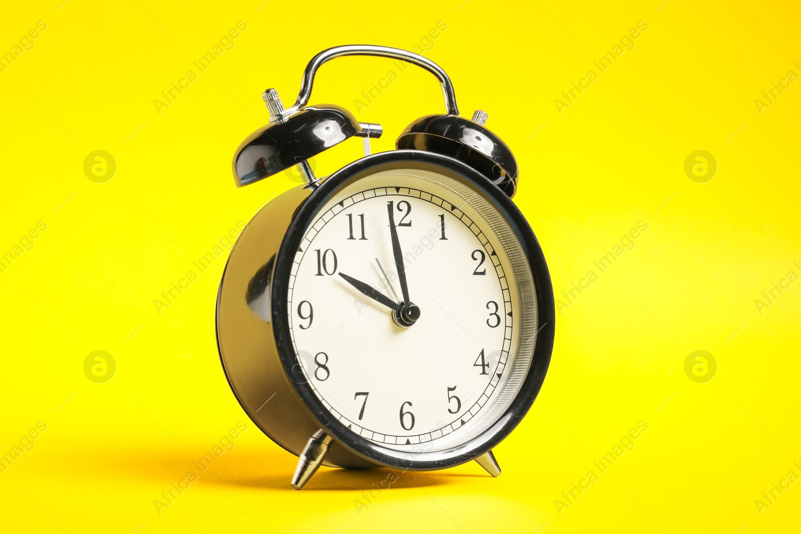 Photo of One black alarm clock on yellow background