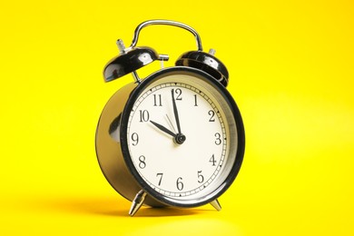 Photo of One black alarm clock on yellow background