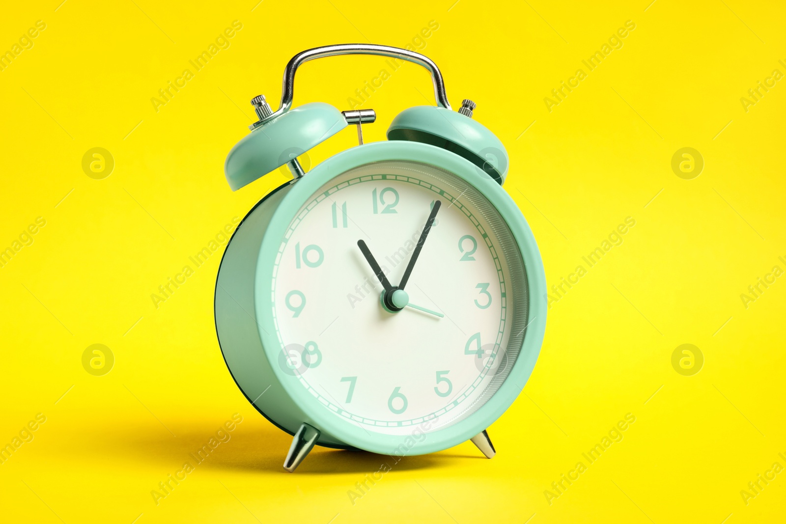 Photo of One turquoise alarm clock on yellow background