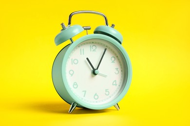 Photo of One turquoise alarm clock on yellow background