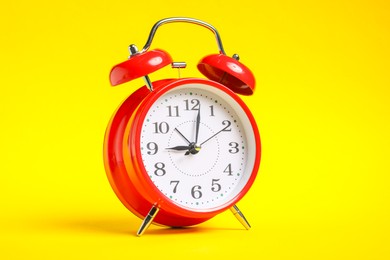 Photo of One red alarm clock on yellow background