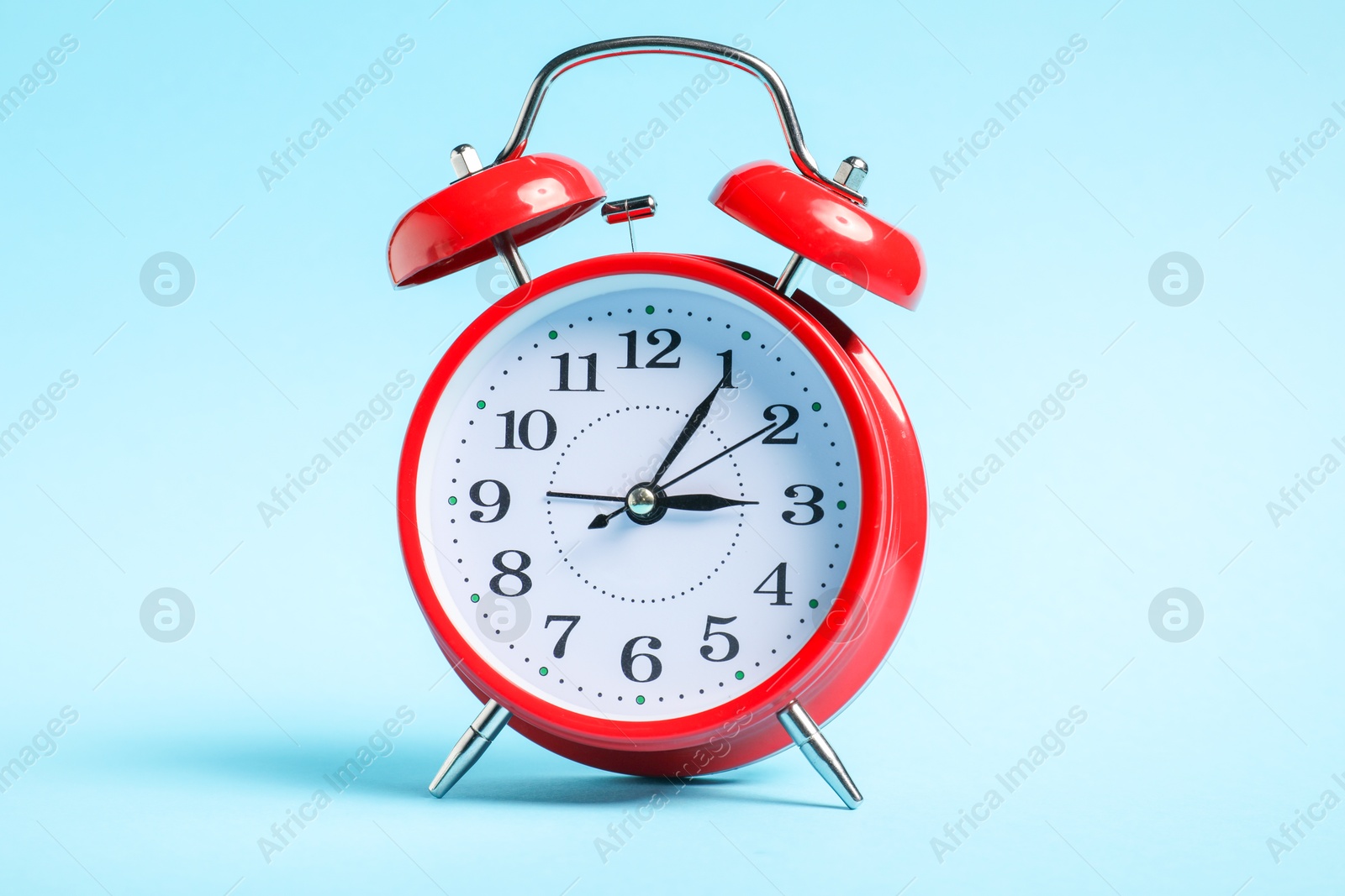 Photo of One red alarm clock on light blue background