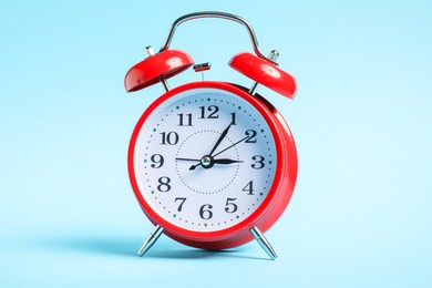 Photo of One red alarm clock on light blue background