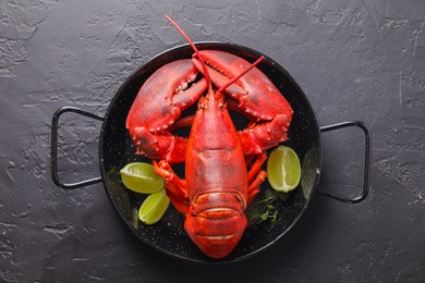 Photo of Delicious boiled lobster with lime pieces and microgreens on black table, top view