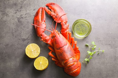 Photo of Delicious boiled lobster with oil, microgreens and lemon pieces on grey table, top view