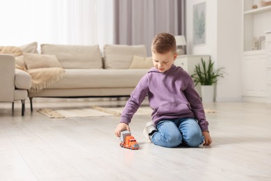 Little boy playing with toy car at home. Space for text