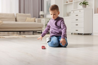 Photo of Little boy playing with toy car at home. Space for text