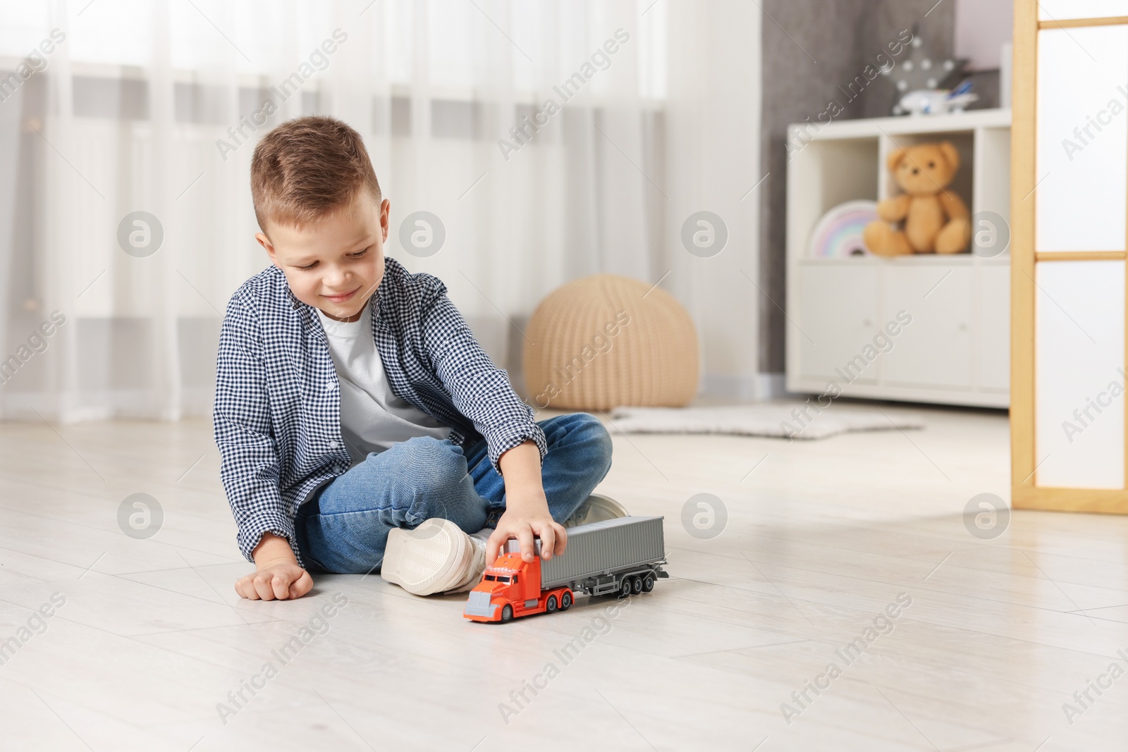 Photo of Little boy playing with toy car at home. Space for text