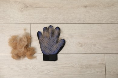 Grooming glove and pile of pet's hair on floor, top view. Space for text