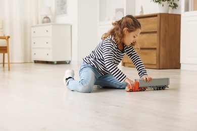 Little girl playing with toy car on floor at home