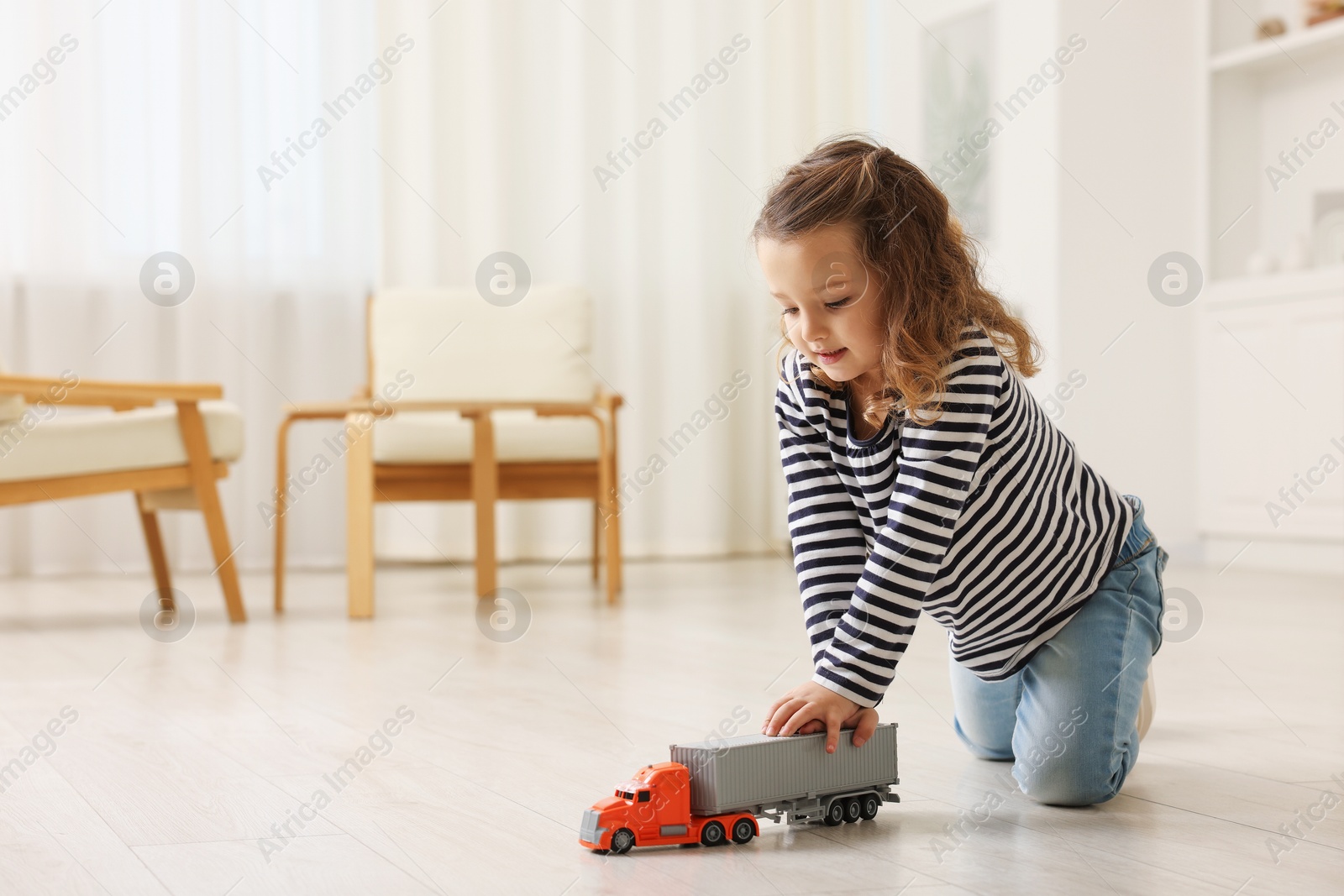 Photo of Little girl playing with toy car on floor at home, space for text