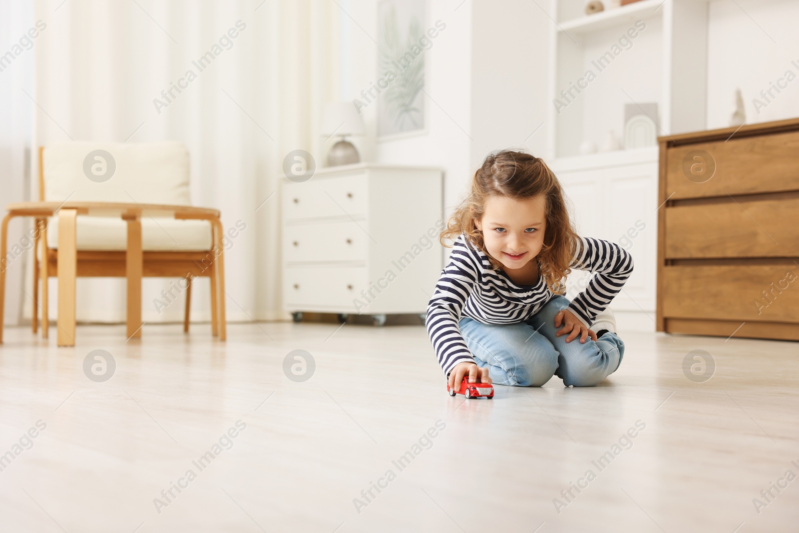 Photo of Little girl playing with toy car on floor at home, space for text