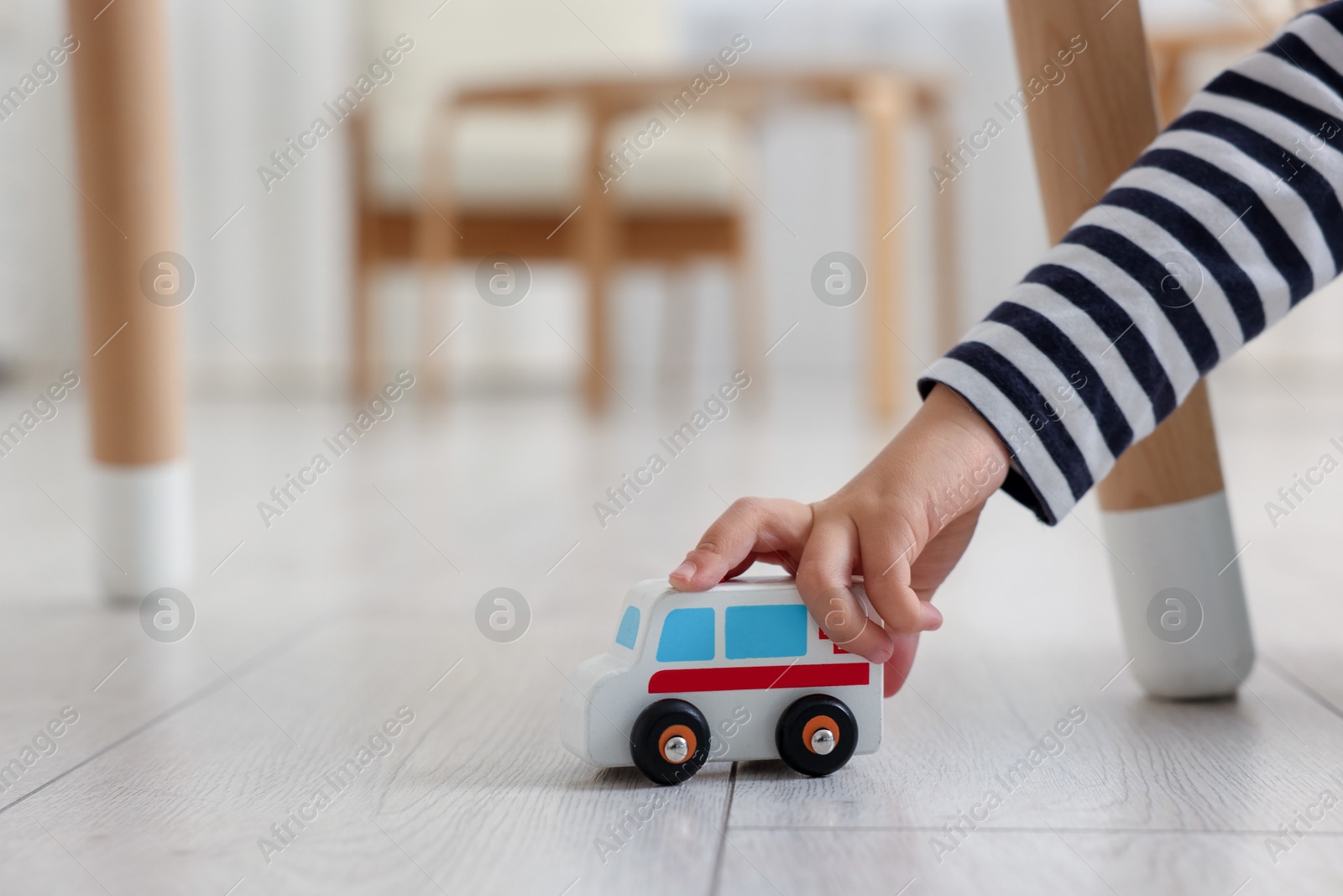 Photo of Little girl playing with toy car on floor at home, closeup. Space for text