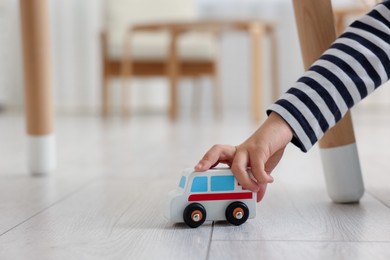 Photo of Little girl playing with toy car on floor at home, closeup. Space for text