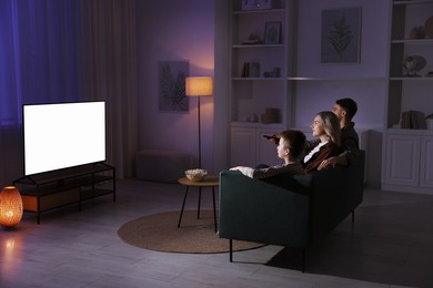 Photo of Happy family watching tv together at home in evening