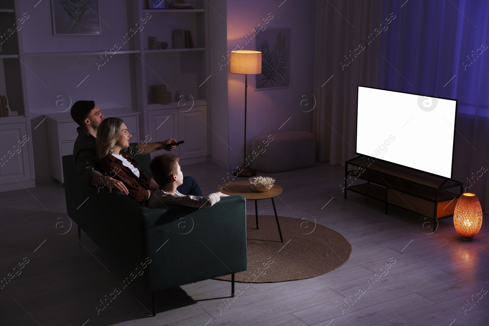 Photo of Happy family watching tv together at home in evening