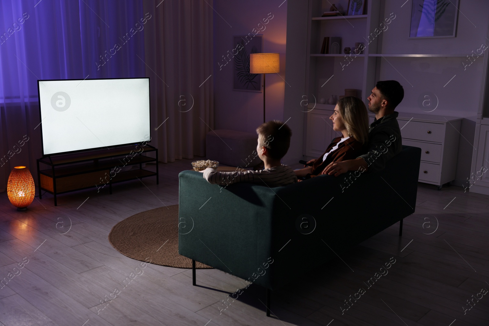 Photo of Happy family watching tv together at home in evening