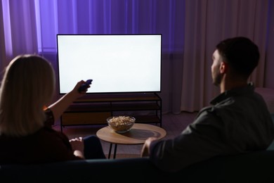 Lovely couple watching tv at home in evening, back view