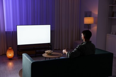 Photo of Man watching tv at home in evening, back view