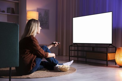 Woman with popcorn watching tv at home in evening