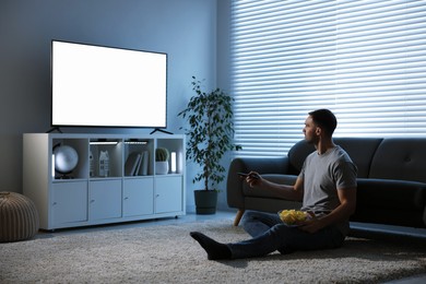 Man with chips watching tv at home