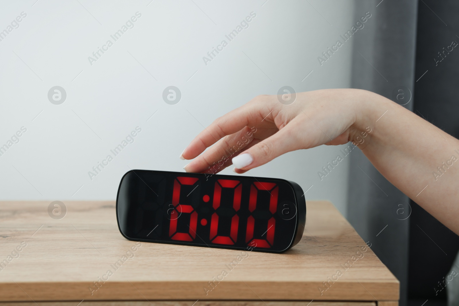 Woman turning off digital alarm clock on bedside table indoors, closeup Photo of Woman turning off digital alarm clock on bedside table indoors, closeup