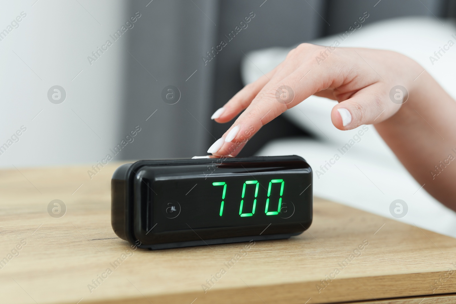 Woman turning off digital alarm clock on bedside table indoors, closeup Photo of Woman turning off digital alarm clock on bedside table indoors, closeup