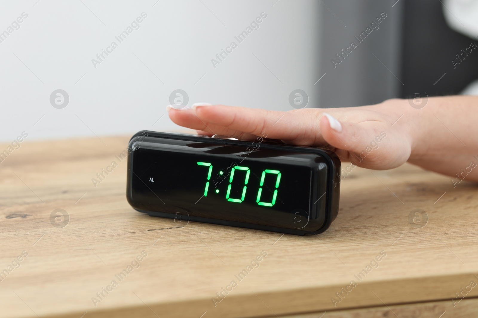 Woman turning off digital alarm clock on bedside table indoors, closeup Photo of Woman turning off digital alarm clock on bedside table indoors, closeup