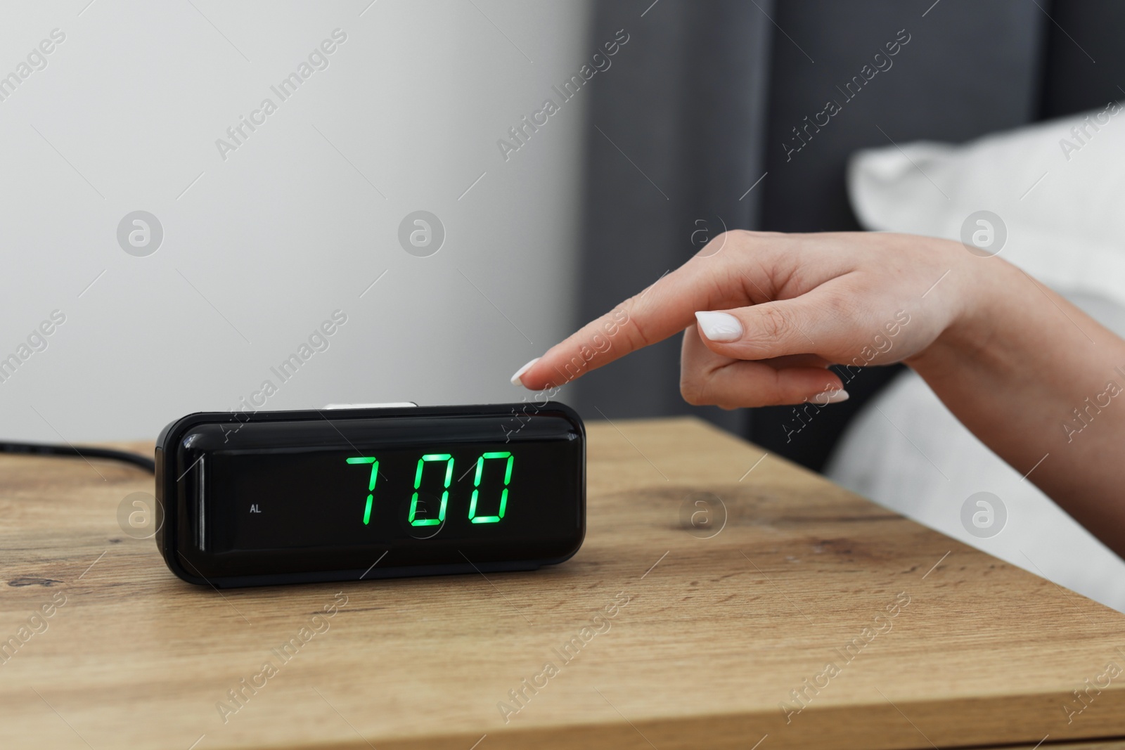 Woman turning off digital alarm clock on bedside table indoors, closeup Photo of Woman turning off digital alarm clock on bedside table indoors, closeup