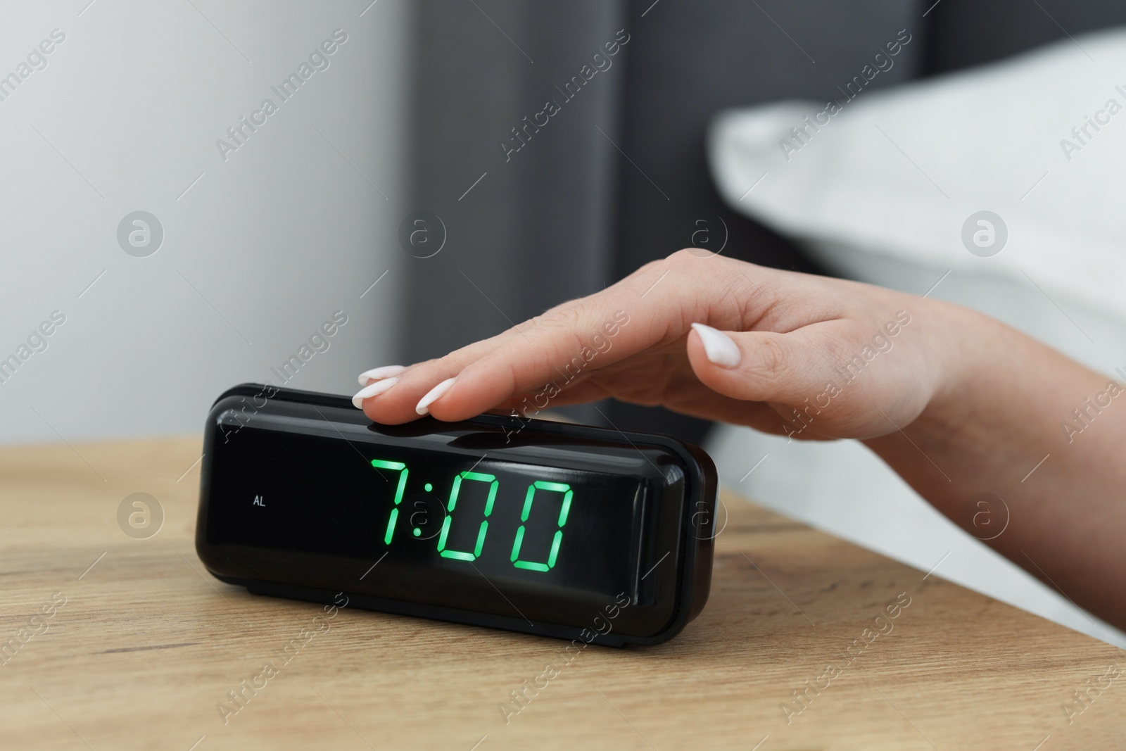 Woman turning off digital alarm clock on bedside table indoors, closeup Photo of Woman turning off digital alarm clock on bedside table indoors, closeup