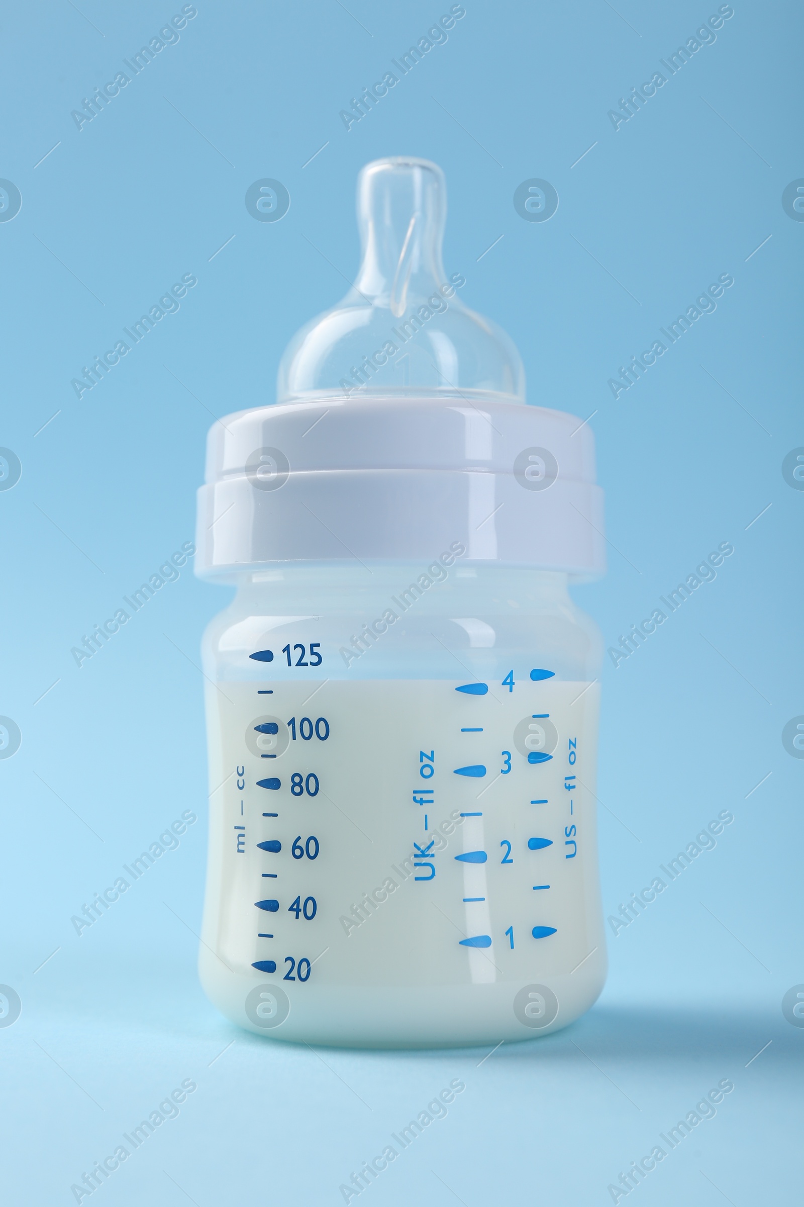 Photo of Feeding bottle with milk on light blue background