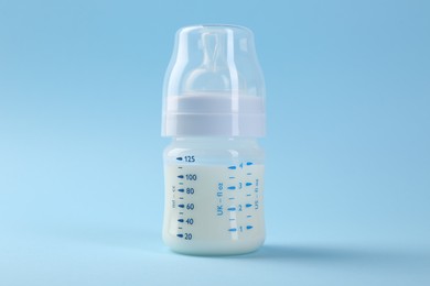 Feeding bottle with milk on light blue background