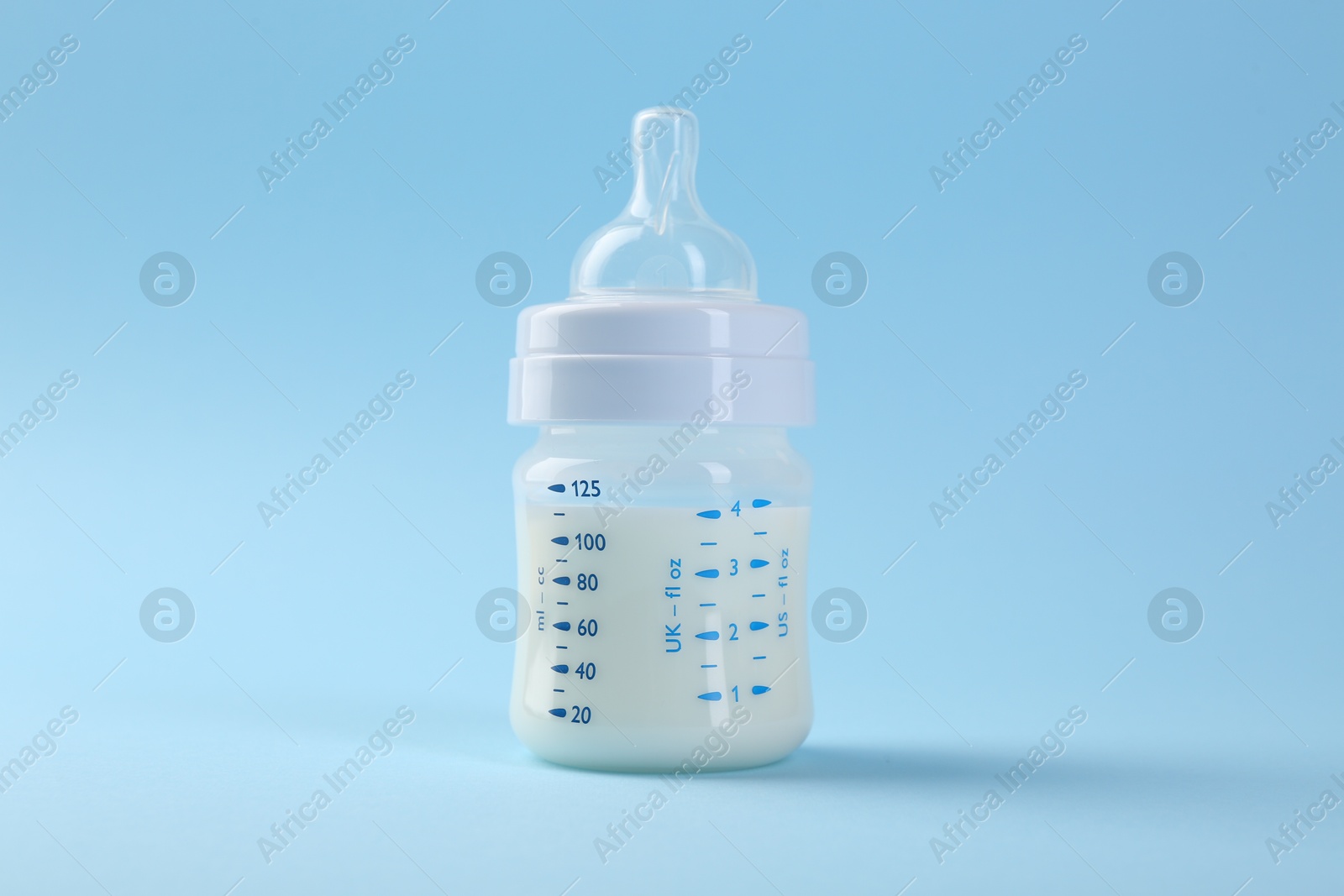 Photo of Feeding bottle with milk on light blue background