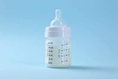 Photo of Feeding bottle with milk on light blue background