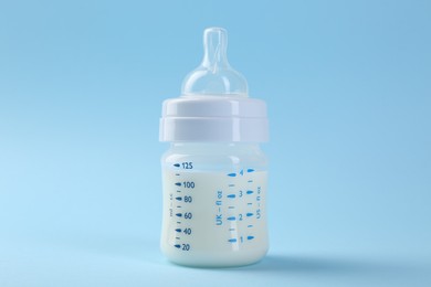 Feeding bottle with milk on light blue background